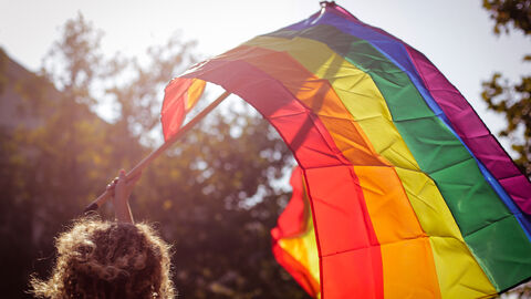 Frau weht Regenbogenflagge durch die Luft Frau weht Regenbogenflagge durch die Luft