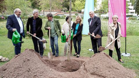 Tag des Baumes 2022 Ministerpräsident Bouffier mit Vertreterinnen und Vertretern des Landtages und der Stadt Wiesbaden, während er eine Schaufel in Händen hält und den Baum einpflanzt.