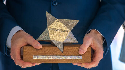 Person hält Walter-Lübcke-Demokratie-Preis in den Händen