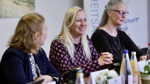 Gesundheitsministerin Stolz sitz mit zwei weiteren Frauen an einem Konferenztisch.