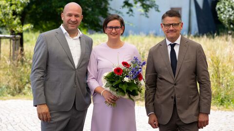Geschäftführerin Christine Müller mit Weinbauminister Jung und Ministerpräsident Rhein Zwei Männer und ne Frau lachen in Kamera. die Frau hält einen Blumenstrauß.