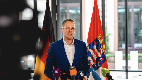 Christoph Degen, Staatssekretär im Hessischen Ministerium für Wissenschaft und Forschung, im Interview vor dem Rüstungsgipfel. Christoph Degen, Staatssekretär im Hessischen Ministerium für Wissenschaft und Forschung, steht vor Mikrofonen in einer Interviewsituation.