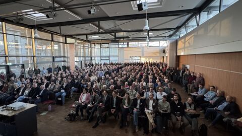 Über hundert Menschen sitzen in in einem Saal.